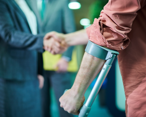 An injured person using crutches shakes hands with a professional in a suit, symbolizing hiring a personal injury attorney for legal help in Oklahoma City.