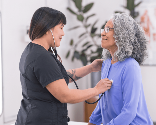 Healthcare provider using a stethoscope to examine an older patient during a medical visit, illustrating the importance of seeking prompt medical care after an injury accident in Oklahoma City.