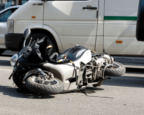 Overturned motorcycle lying on a roadway beside a vehicle, depicting a serious crash scene in Oklahoma City and highlighting the severe injuries riders can suffer in motorcycle accidents.