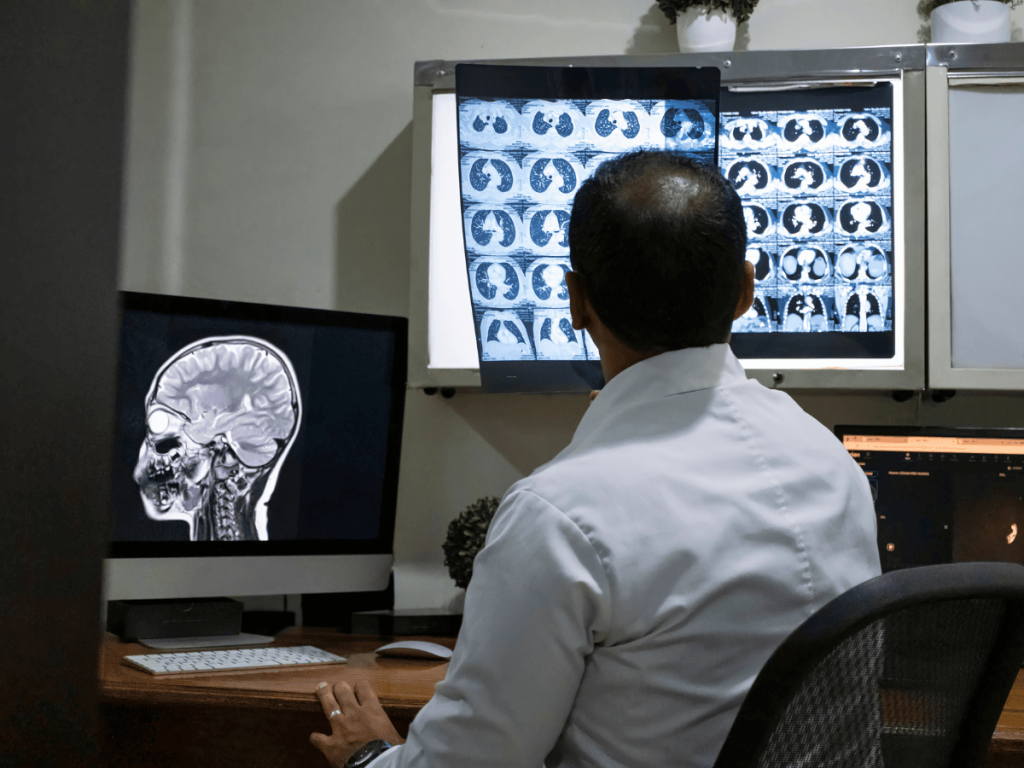 Doctor reviewing CT scans and medical imaging studies on diagnostic monitors, illustrating remote radiology interpretation, imaging errors, and potential medical malpractice claims.