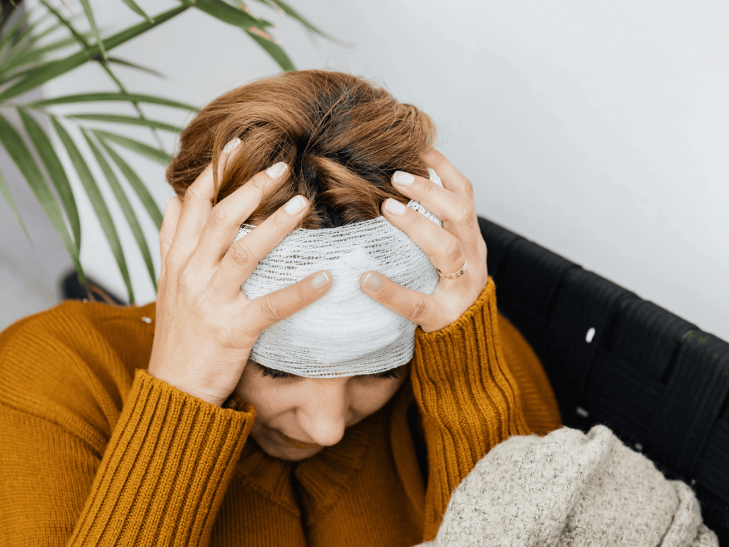 Woman with a head injury holding her head in distress, illustrating common traumatic brain injury symptoms such as headaches, sensitivity, and cognitive issues after an accident in Oklahoma City.