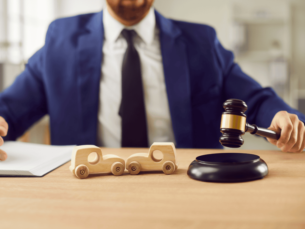 Attorney holding a gavel over a desk with small model cars, symbolizing legal decisions and insurance disputes following a car accident in Oklahoma City.
